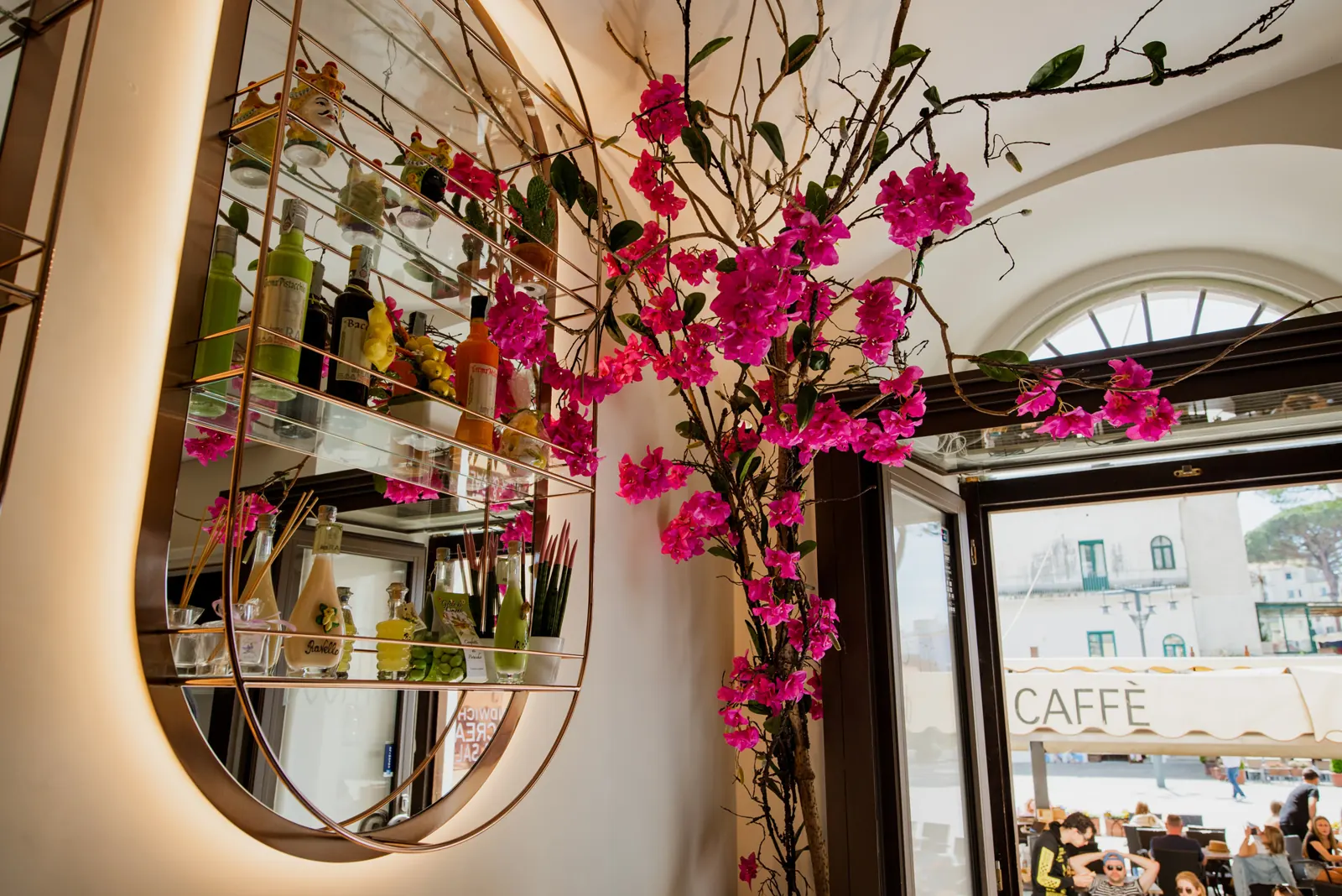 Lo specchio ad arco con le bottiglie e i fiori di bouganville